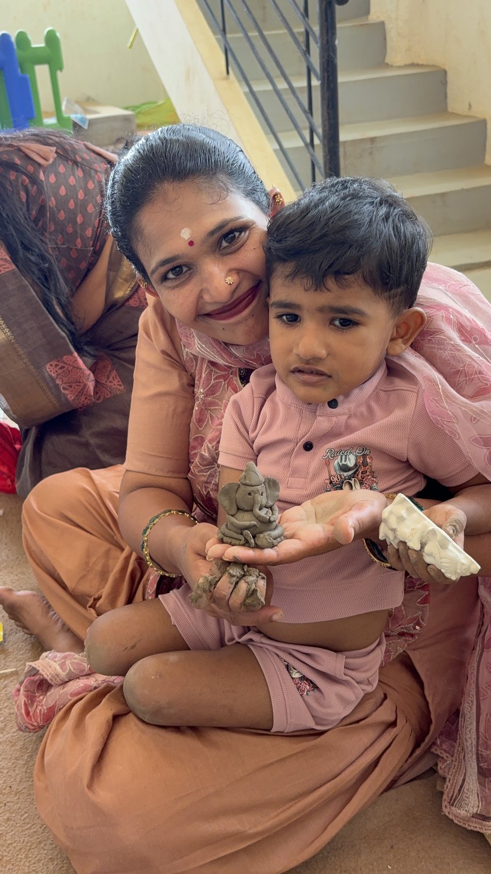 A child sharing a handmade clay form with a family member