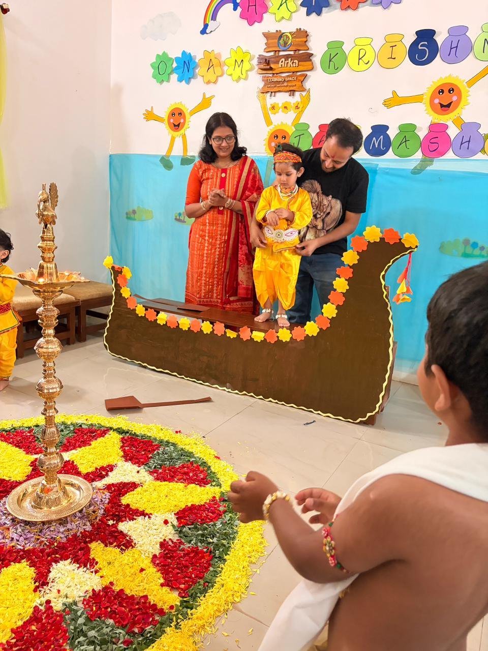 Children celebrating Krishna Janmashtami beside the flower display