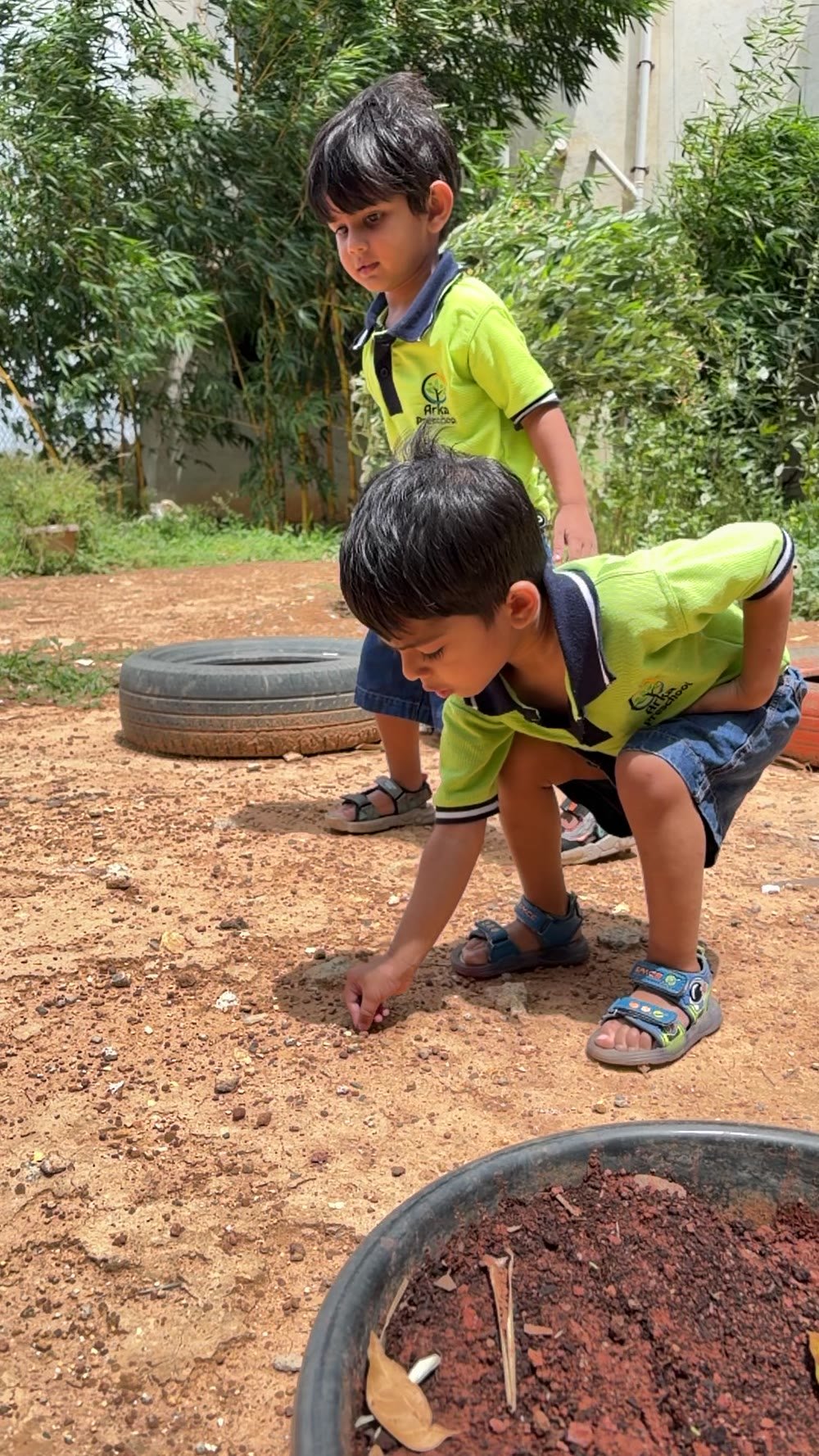Two children closely exploring the outdoor ground