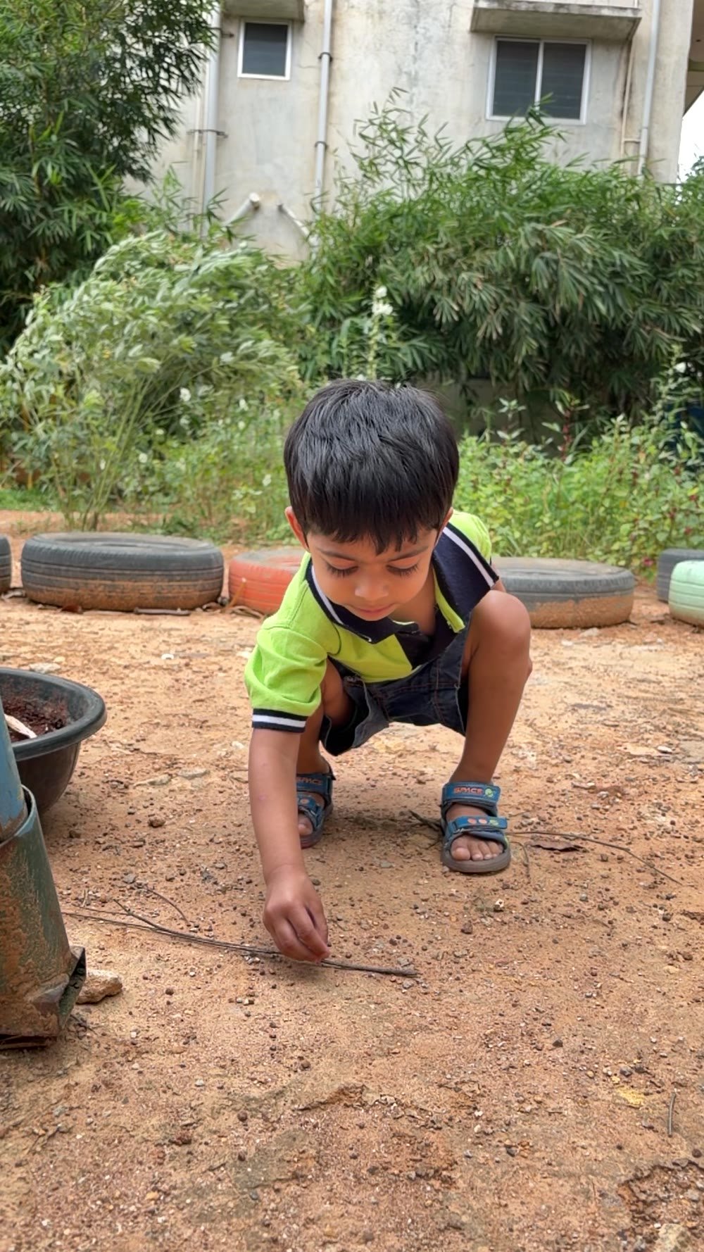 An Arka child carefully discovering a small object outdoors