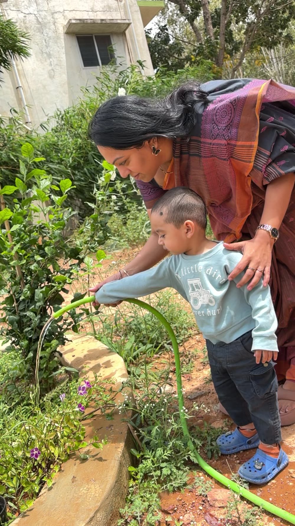 An educator and child watering flowering plants together