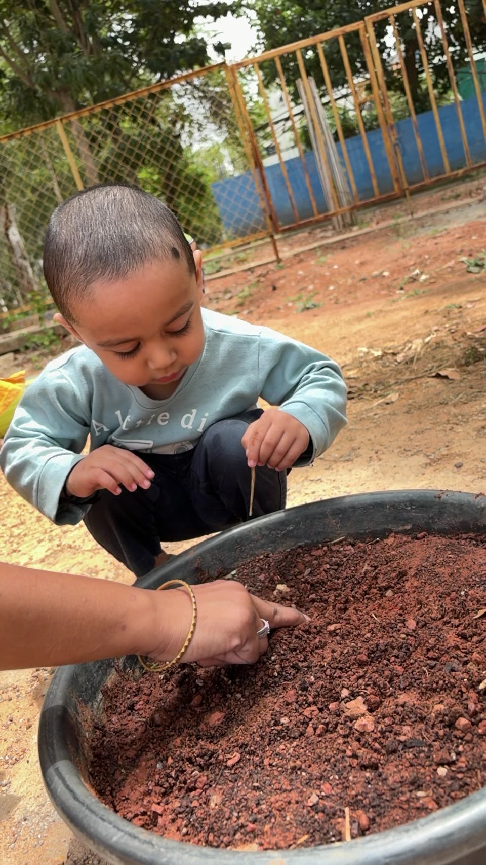 An Arka child and educator exploring the texture of soil