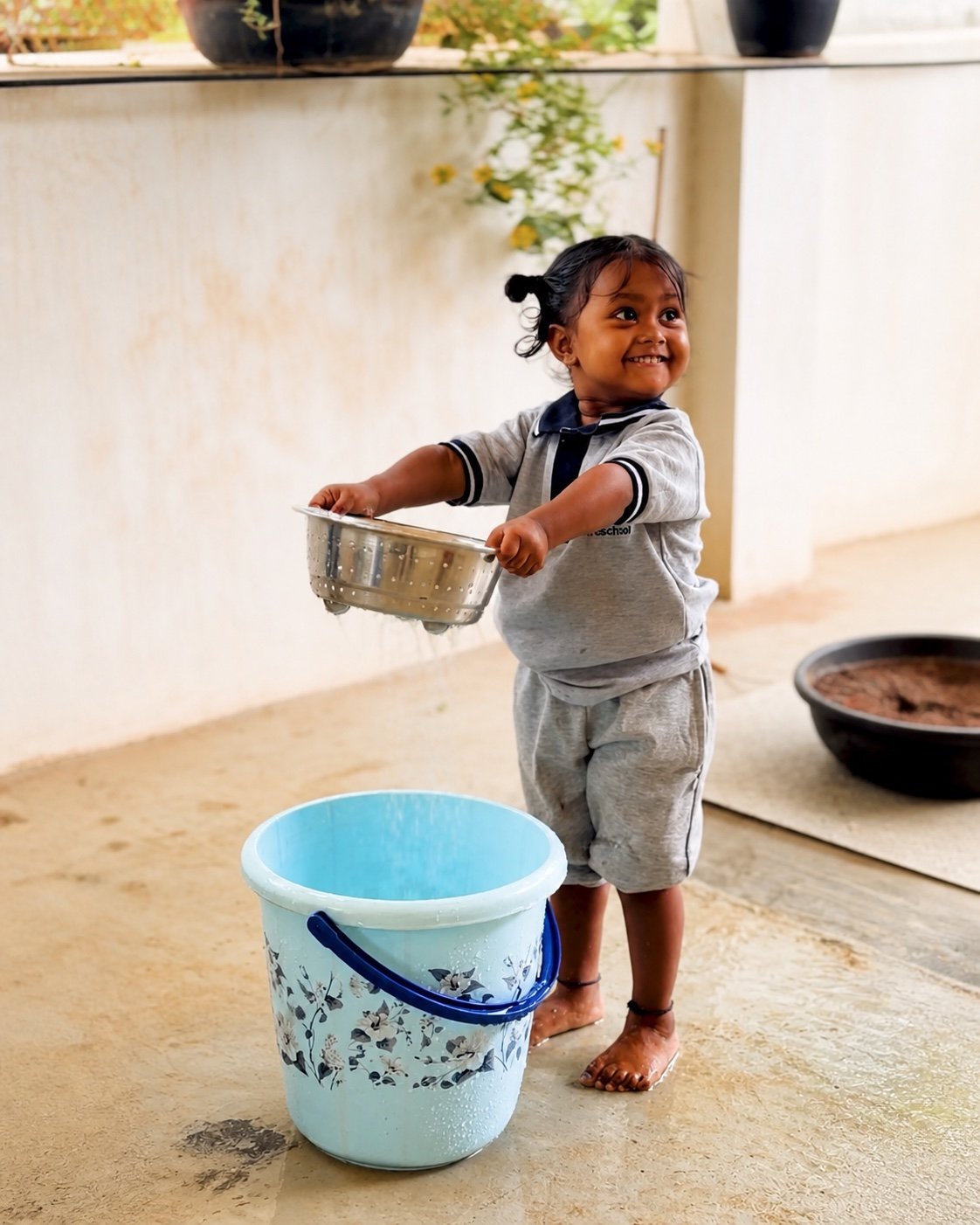 Young Arka child carrying a bowl during water play
