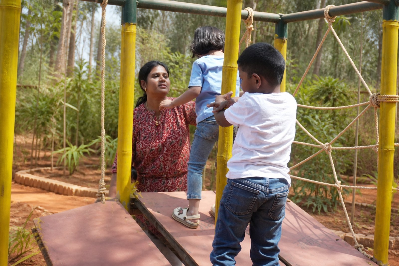 Children and educator navigating the outdoor bamboo play structure