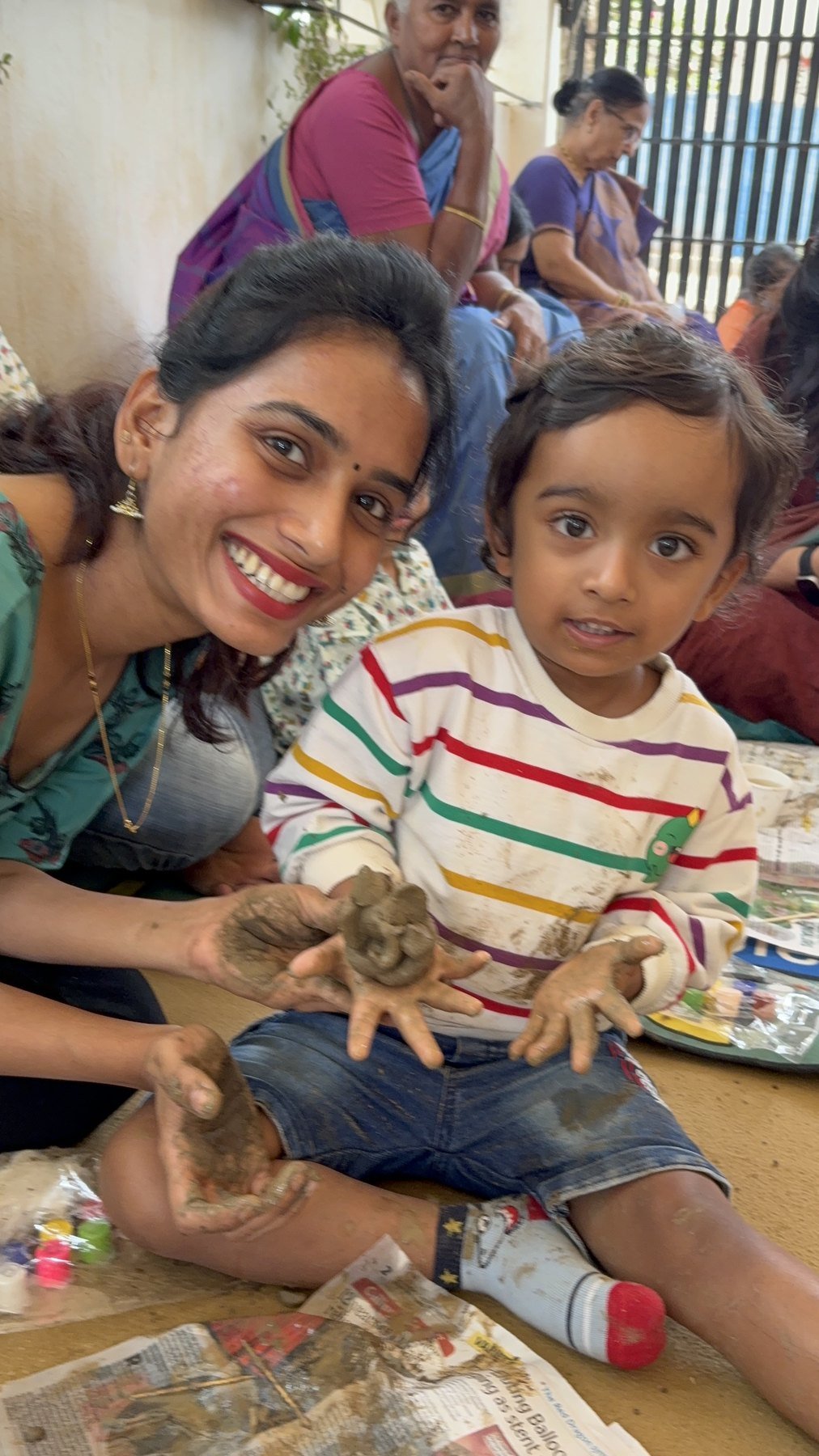 An educator and child smiling together over a clay creation