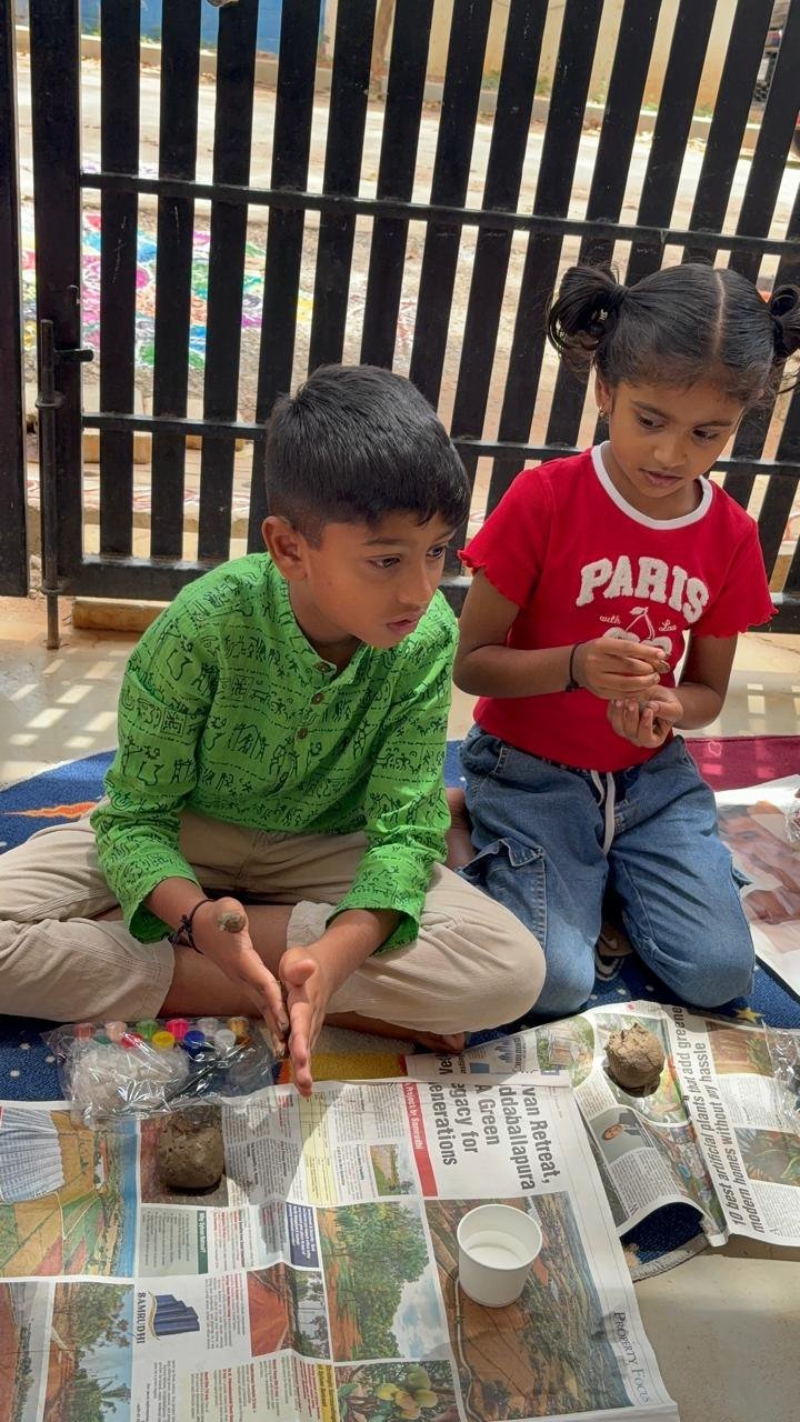 Two children shaping clay together for Ganesha Chaturthi