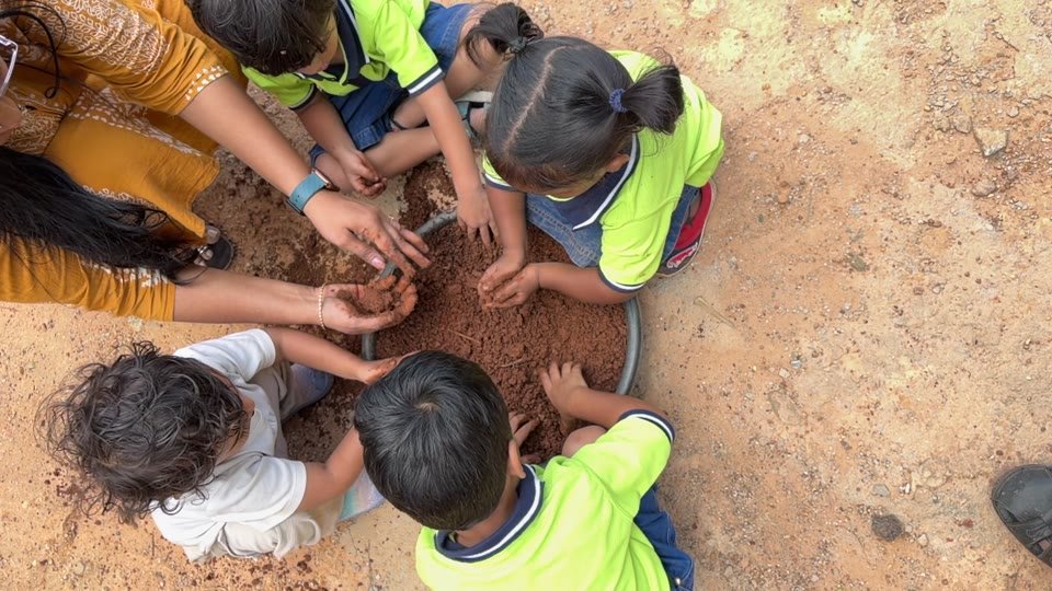 Children gathering around soil with an educator
